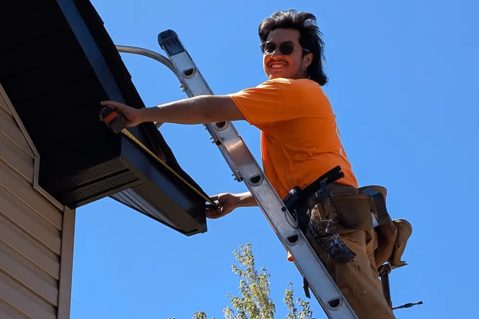 Luiz on a ladder working on dark fascia