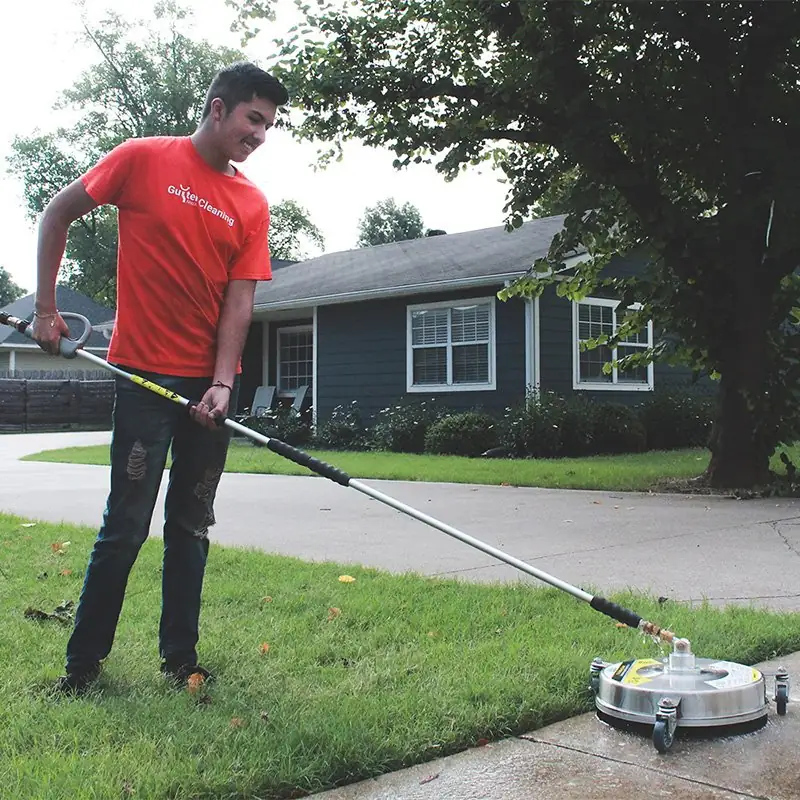 Luiz from the Chappell Gutter crew surface-cleaning a driveway with a pressure washer